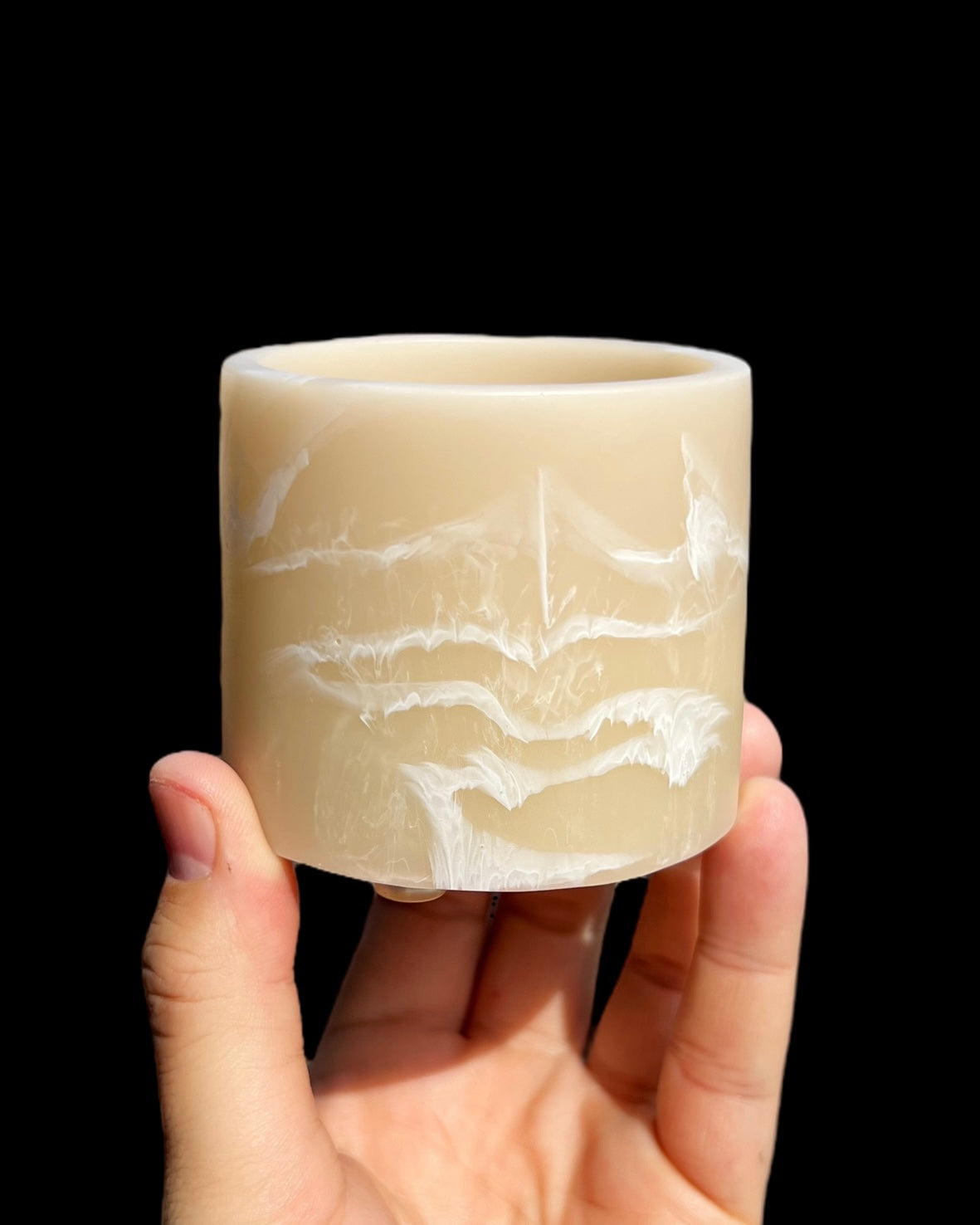 A hand holding a handmade beige and white striped custard planter pot.